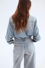 Pantalón de jean celeste de corte ancho, tiro alto y largo tobillero.