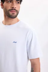 Camiseta de manga corta celeste con cuello redondo y pequeño bordado de una ola en el pecho.