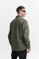 Sobrecamisa verde militar de twill de algodón, con cuello clásico, cierre frontal con botones a tono, dos bolsillos tipo parche con solapa abotonada en el pecho, mangas largas con puños abotonados y corte recto.