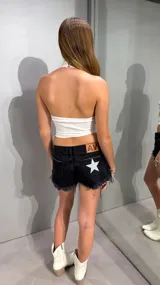 Top halter blanco con apliques metálicos y tachas plateadas distribuidas por toda la prenda.
