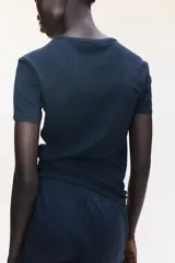 Remera negra entallada de punto de algodón elástico, con cuello redondo fino ribeteado y bajo recto.