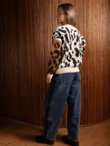 Saco tipo cárdigan de tejido suave y peludo, con estampado animal print en tonos beige, negro y marrón. Presenta cuello en V, cierre frontal con botones y mangas en contraste de color con diseño animal print.