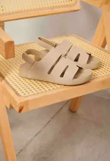 Sandalias planas color beige, estilo romano con tiras anchas ranuradas y tira ajustable en el talón.
