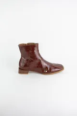 Botinetas de cuero con textura croco acharolado en color negro. Presentan un diseño de punta cuadrada, cierre lateral y un taco bajo de madera.