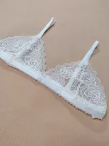 Bralette de encaje blanco con diseño de rosas, copas triangulares y tirantes finos ajustables.