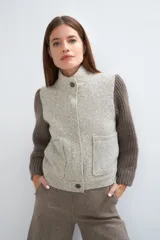 Campera de lana fina color crema, con cuerpo estructurado y mangas de tejido de punto acanalado. Presenta cuello alto, cierre frontal con botones y bolsillos laterales con doble abertura.