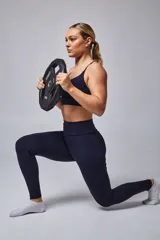 Top deportivo color beige con contorno inferior y tiras cruzadas en la espalda color borgoña. Cuenta con almohadillas removibles.