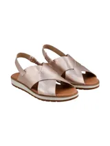 Sandalias de cuero metalizado en tono rosado, con tiras cruzadas en el empeine, tira ajustable en el talón y suela plana con plataforma baja y base dentada.