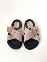 Sandalia de cuero vacuno color rosado, con tiras cruzadas en el empeine y una hebilla metálica dorada como detalle. Cuenta con suela de goma negra.