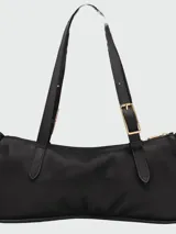 Cartera de hombro de diseño minimalista y estructura rectangular, confeccionada en cuero liso color beige. Cuenta con una correa ajustable con hebilla metálica y cierre superior con cremallera.