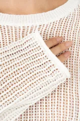 Suéter de punto calado en tono marfil, con diseño corto y holgado, cuello redondo y mangas largas.