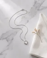 Collar de acero con dije en forma de trébol relleno de nácar blanca y borde con incrustaciones de circones.