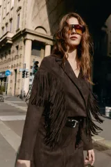 Chaqueta corta de Zara confeccionada en tejido efecto ante color marrón oscuro. Presenta cuello con solapas de muesca, manga larga y detalle de flecos en el mismo tejido a lo largo del pecho y la espalda. Cierre frontal cruzado con botones ocultos.