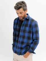 Camisa de franela a cuadros en tonos azul y negro, con cuello clásico, cierre frontal de botones y bolsillo en el pecho.