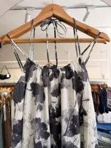Vestido largo de modal con estampado floral en tonos blanco y negro, de silueta amplia y caída fluida, escote fruncido y tiras finas para atar al cuello. Cuenta con forro corto interno y tajo en la espalda.