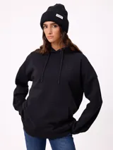 Gorro tipo beanie de punto acanalado color bordó, con etiqueta rectangular blanca con logo de la marca en el frente.