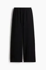 Pantalón de punto de algodón color negro, de corte recto y holgado. Cuenta con cintura elástica ajustable mediante cordón y bolsillos laterales discretos.