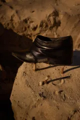 Botineta de gamuza azul marino con diseño drapeado, punta fina con puntera metálica y placa metálica decorativa en el lateral. Posee taco bajo cuadrado.