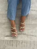 Sandalias planas color beige con tiras cruzadas y tachas doradas.