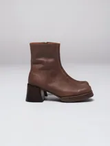 Botas de caña corta en gamuza color beige, con plataforma y taco cuadrado de madera oscura. Presentan cierre lateral interno.