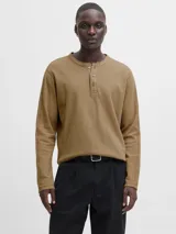 Camiseta de manga larga con cuello henley y cierre frontal de tres botones. Confeccionada en algodón orgánico de textura suave, presenta un corte regular y diseño clásico.