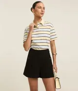 Short sastre de cintura alta con estructura definida, bolsillos laterales decorados con tachuelas metalizadas y recortes delanteros con costura aparente.