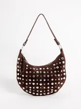 Cartera tipo hobo de gamuza marrón, adornada con múltiples tachas metálicas plateadas en toda su superficie. Cuenta con cierre superior y una única asa de hombro ajustable mediante argollas metálicas.