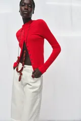 Chaqueta de punto extrafino color negro con cuello redondo y manga larga. Cierre frontal con hilera de botones pequeños.