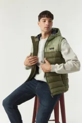 Chaleco inflable verde oliva con capucha ajustable, cierre frontal y bolsillos laterales con cierre.