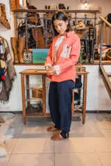Sobre camisa coral de manga larga, con canesú en la espalda y detalles en los puños de tela estampada con flores.