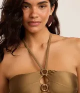 Top de bikini bandeau color verde oliva, con tirantes finos al cuello y detalle de aros de paja en el centro.