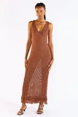 Vestido largo de punto abierto color marrón con sutil brillo de lúrex, sin mangas, con escote en V y detalle de flecos en el ruedo.