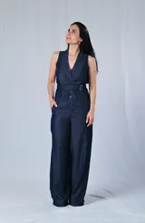 Chaleco de jean azul con cuello en V, corte al cuerpo y cierre cruzado con cinturón con hebilla metálica.