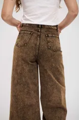 Pantalón de jean de corte wide leg con efecto de lavado ácido en tono marrón. Presenta tiro alto, cierre frontal con botón y bolsillos laterales.
