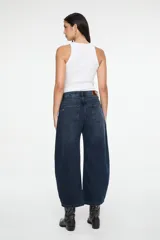 Pantalón de denim azul oscuro con corte balloon, tiro medio, costuras curvas decorativas en el frente y diseño de cinco bolsillos.