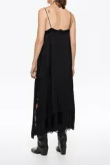 Vestido midi negro de silueta línea A, confeccionado en viscosa, con escote en V profundo y tirantes finos. Presenta detalles de encaje en el escote y en el bajo, con una abertura lateral adornada con encaje.