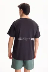Remera negra de manga corta con corte semi boxy y estampado de texto en la espalda.