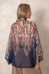 Camisa oversize de gasa con estampado de cadenas en tonos bordó y rosado. Presenta cuello clásico, cierre frontal con botones y mangas largas con puños abotonados.