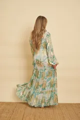 Vestido largo con estampado floral en tonos verde agua y detalles metalizados dorados, con escote en V, mangas largas abullonadas y falda de diseño escalonado.