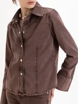Camisa entallada confeccionada en denim de algodón con lavado marrón chocolate, cuello camisero, cierre frontal con botones y recortes verticales.
