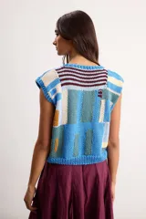 Chaleco de punto tejido a mano con diseño geométrico multicolor en tonos azules, celestes, beige y marrón, sin mangas y con escote redondo.