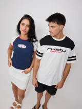 Remera blanca de hombre con corte negro en la parte superior del pecho y mangas cortas con tres rayas horizontales negras. Estampado frontal con el logo de Rusty en negro y la palabra 'Culture' en rojo.