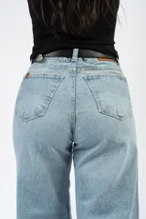Jean de corte campana con tiro medio, confeccionado en denim con elastano. Presenta un lavado claro y ruedo deshilachado.