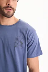 Remera azul de manga corta con estampa en la espalda de diseño tipo estampilla con paisaje de palmeras, olas y montañas.