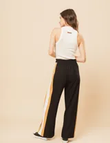 Pantalón palazzo color beige con cintura elastizada y dos franjas verticales en los laterales, una plateada y otra blanca.