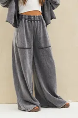 Pantalón gris con efecto acid wash, tiro alto con cintura elástica fruncida, corte amplio tipo palazzo y grandes bolsillos frontales aplicados.