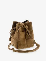 Cartera tipo bucket de gamuza color marrón con diseño trenzado, cierre con lazo ajustable y correa larga para llevar cruzada.