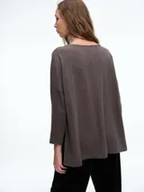 Buzo tejido de silueta relajada con sisa caída y tajos laterales que aportan movimiento. Presenta cuello redondo y mangas tres cuartos.