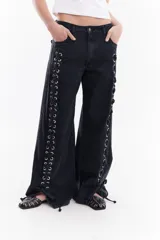 Jean wide leg de tiro medio color negro, con ojalillos metálicos y cordones de denim entrecruzados a lo largo de las costuras laterales.