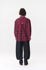 Camisa de corte holgado en color bordó con estampado de cuadros y monograma. Presenta cuello redondo con borde de puntilla, bolsillo frontal con detalle de puntilla, cierre frontal con botones y puños con terminación en puntilla.